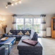 modern eingerichtetes Wohnzimmer mit Couch und Essbereich, Glastüren zur Terrasse