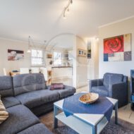 modern eingerichtetes Wohnzimmer mit Couch und Essbereich, Glastüren zur Terrasse